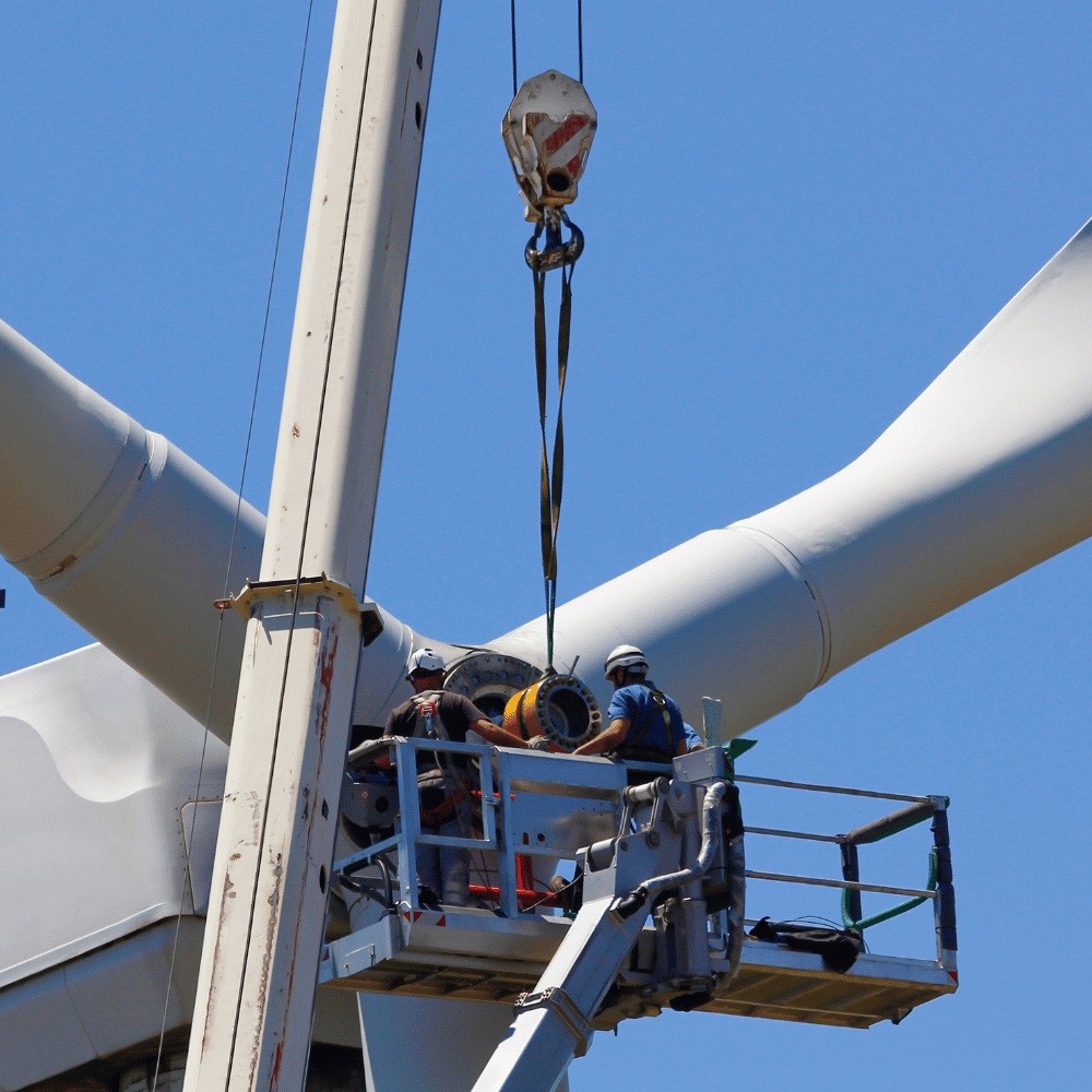 Techniker montieren ein Rotorblatt an einer Windkraftanlage – Isolierungen für die Energieversorgung