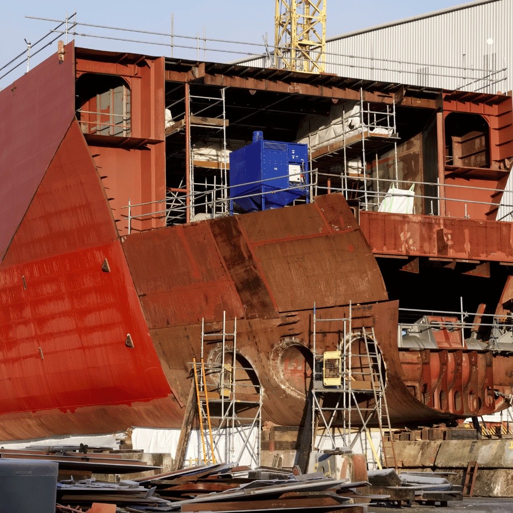 Schiffsrumpf im Bau auf einer Werft mit Gerüsten und Kran – maritime Isolierungen für Schiffsbau und Offshore